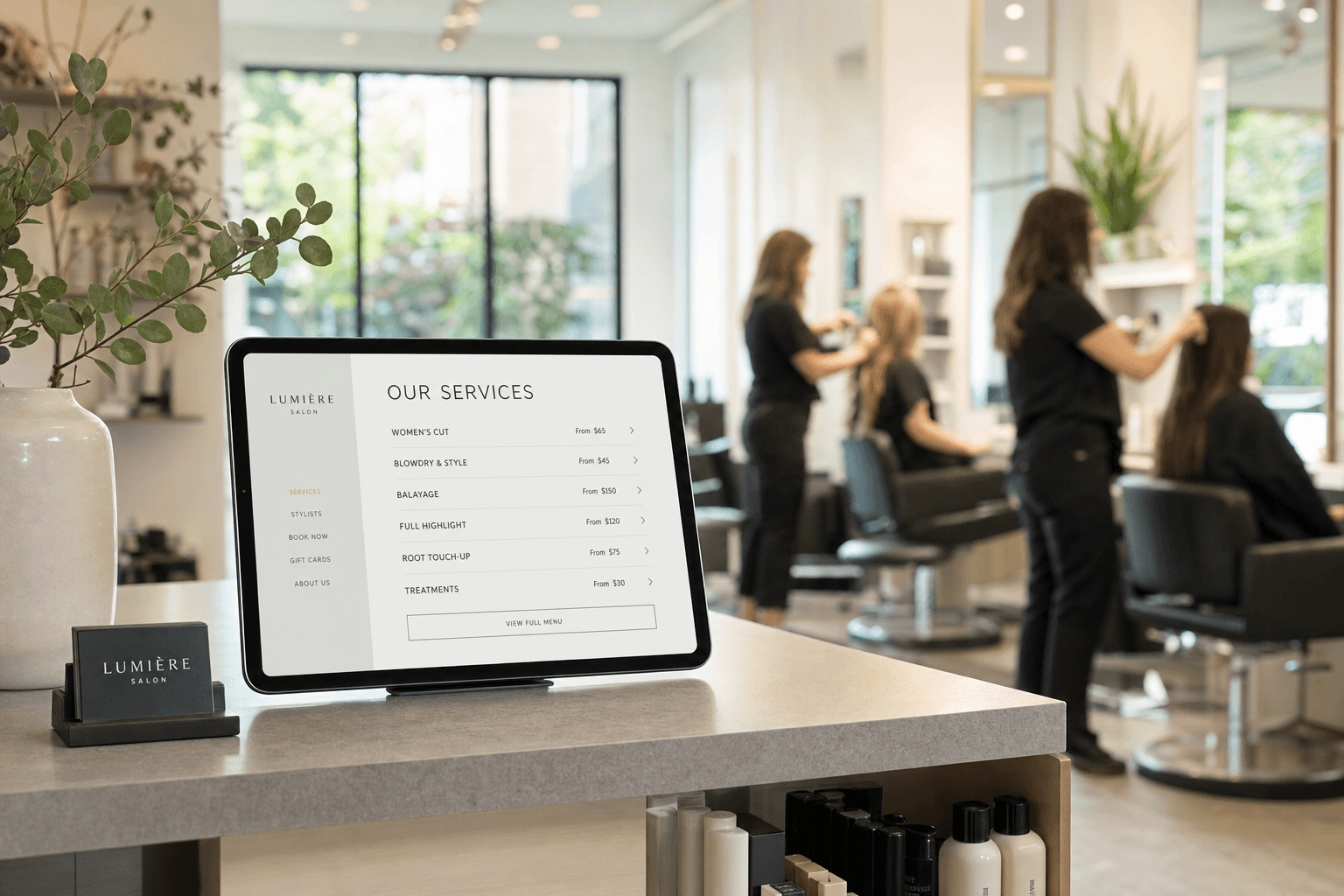 A modern hair salon reception desk with a tablet displaying a digital service menu